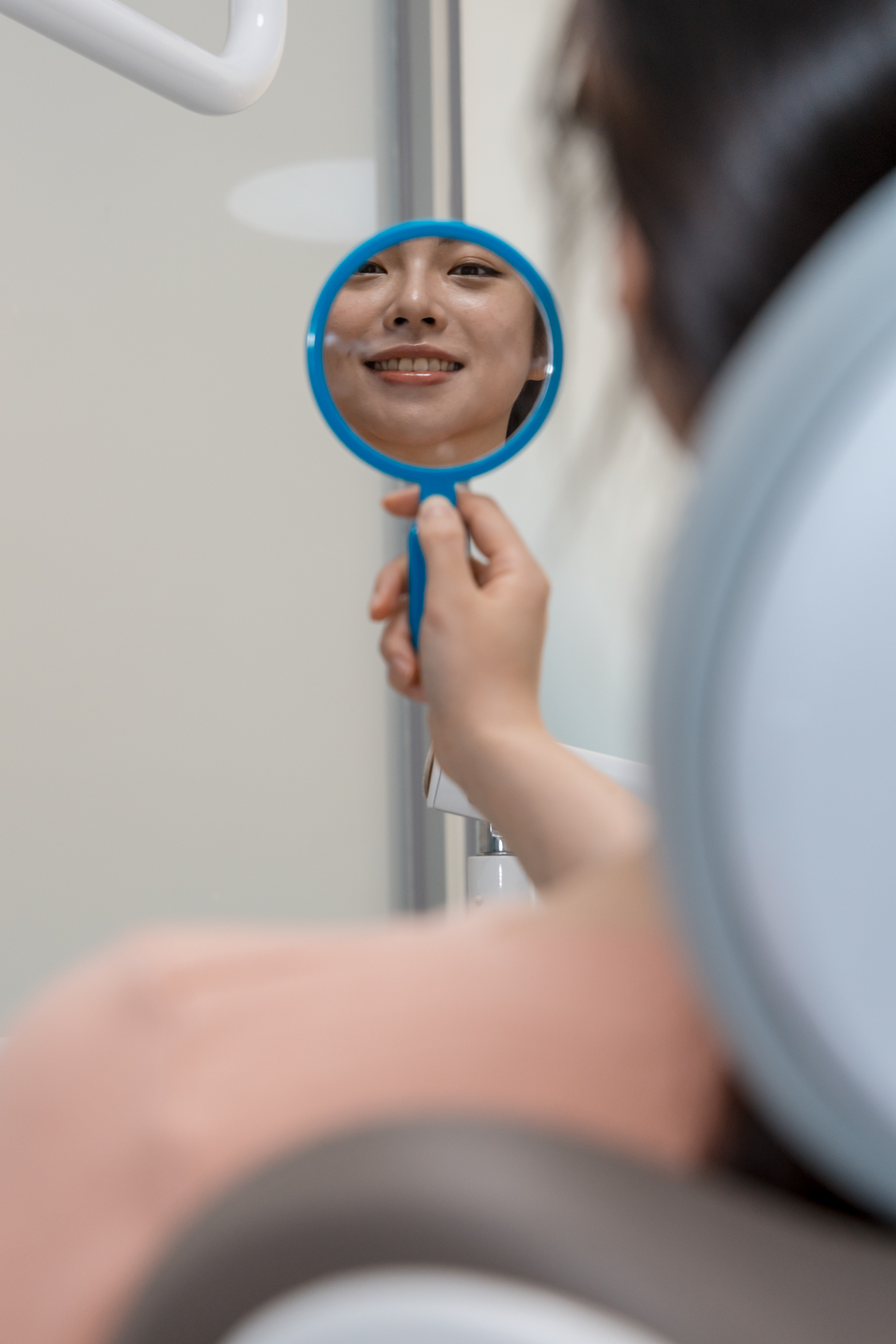 Happy patient looking in a mirror to see the natural appearance of her new dentures.