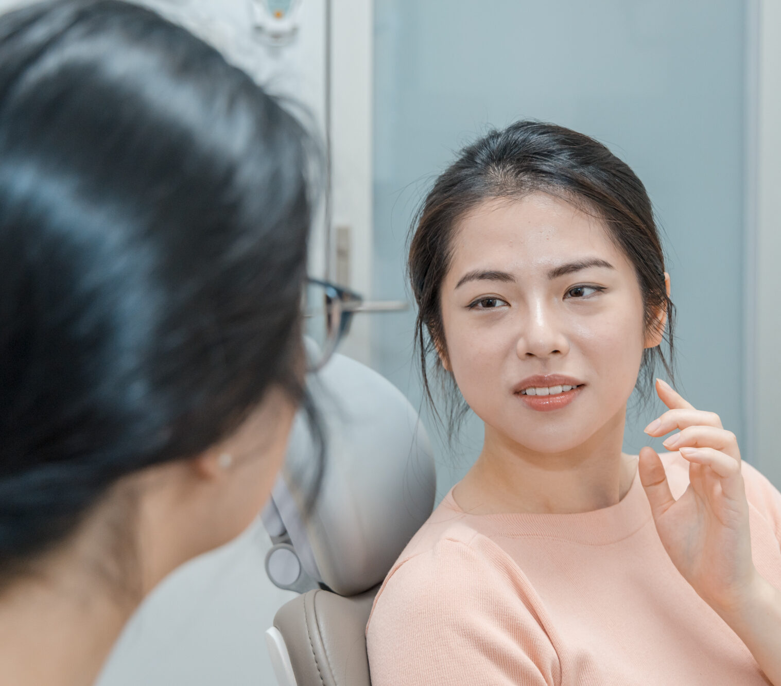 A patient talks to her dentist about jaw pain prior to her wisdom teeth removal procedure.