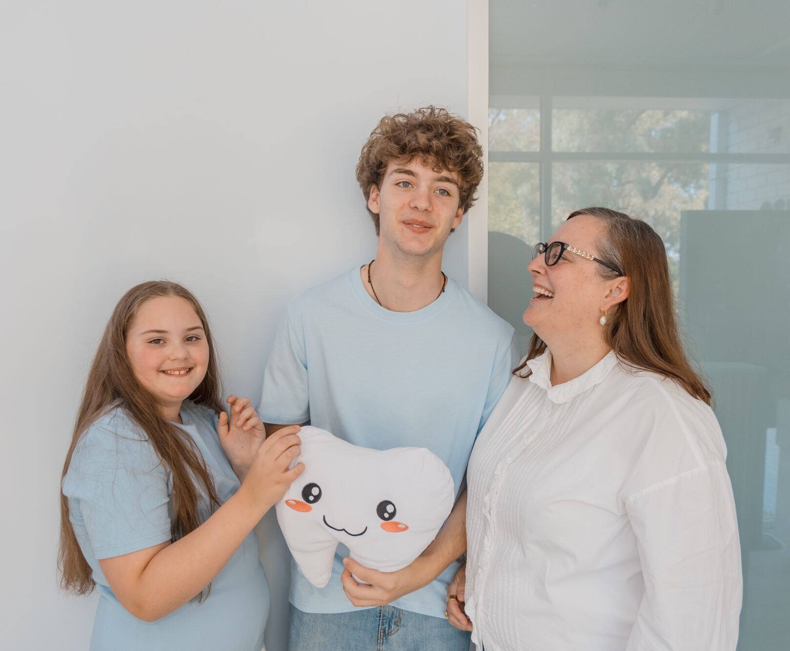 A happy family smiles and laughs during a visit, showcasing a stress-free pediatric root canal experience.