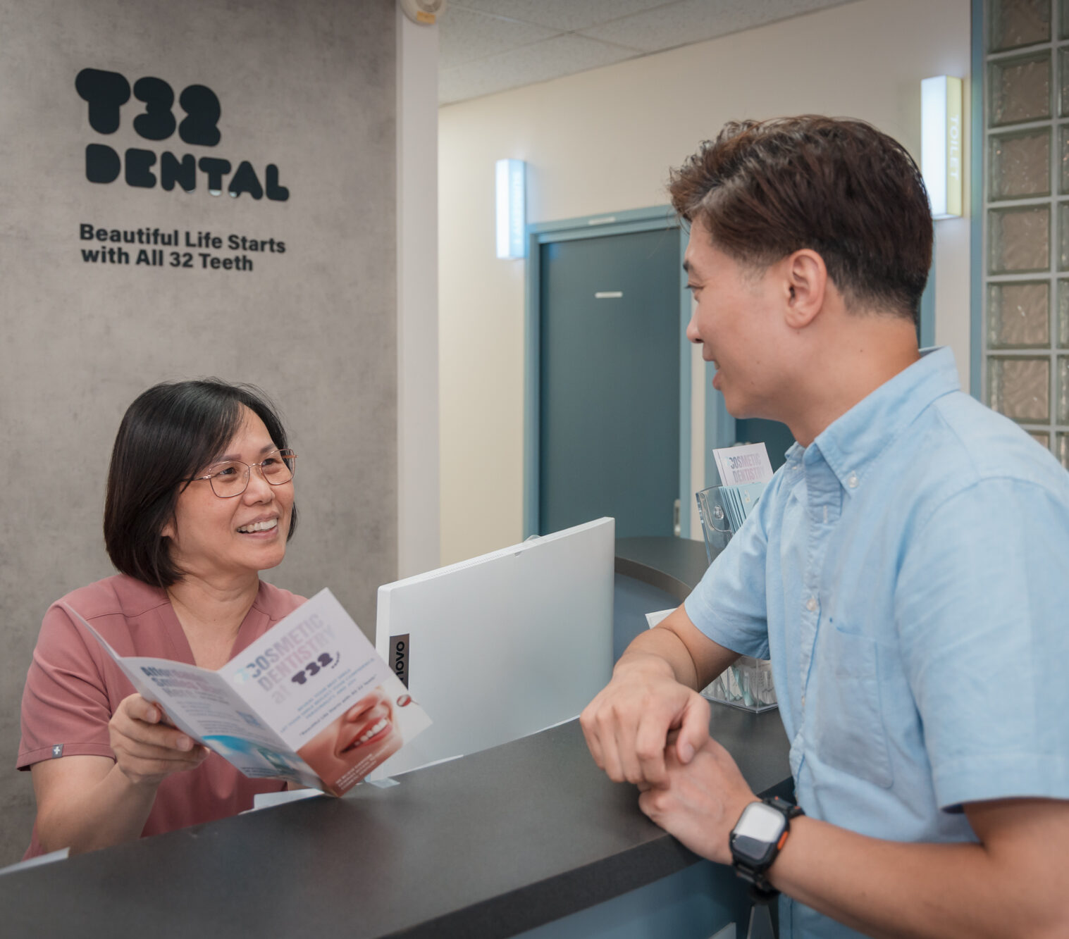 Welcoming receptionist assisting a new patient at the reception desk of a general dentistry clinic.