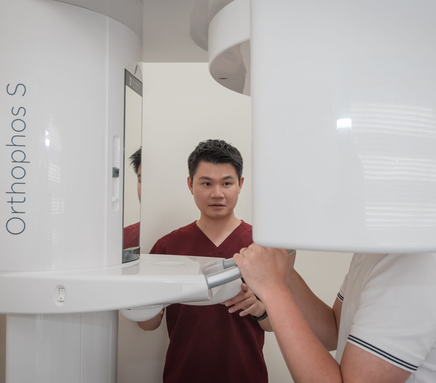 A patient prepares to receive a dental x ray scan guided by a clinic practitioner using modern medical equipment.