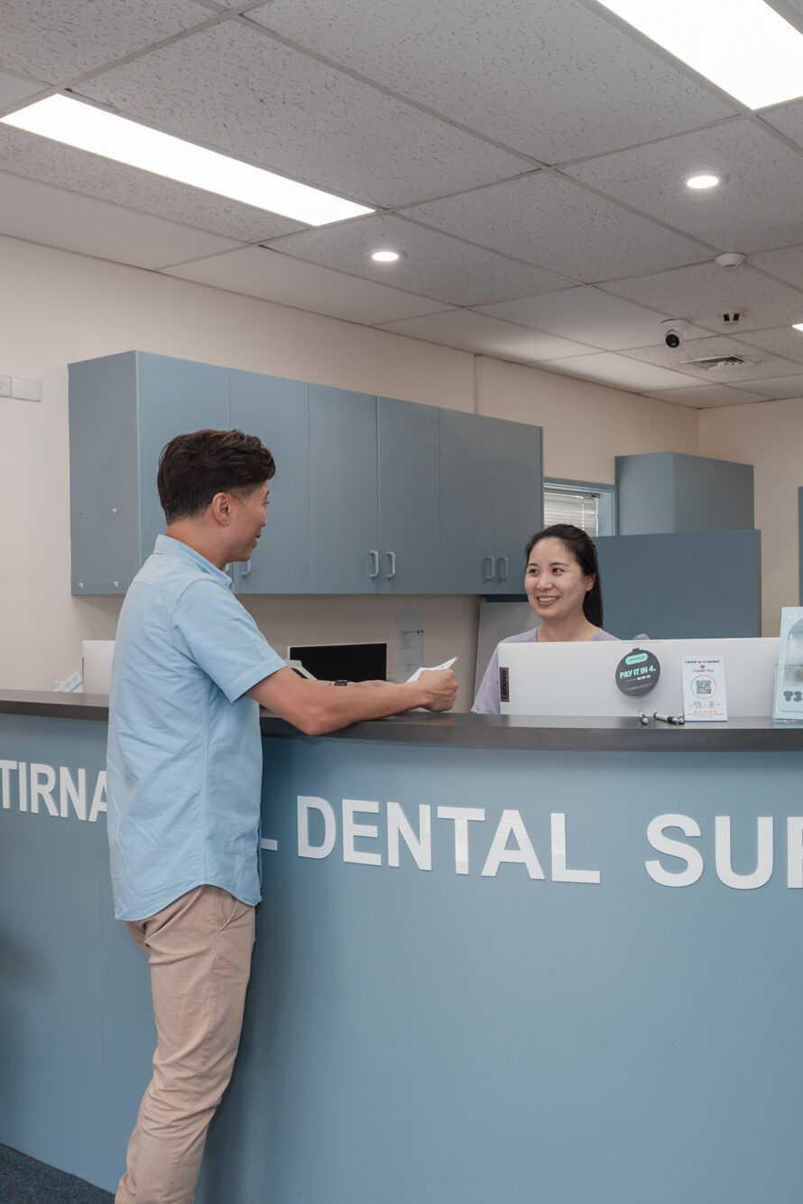 A patient arriving at the dental clinic reception desk for a routine scale cleaning appointment.