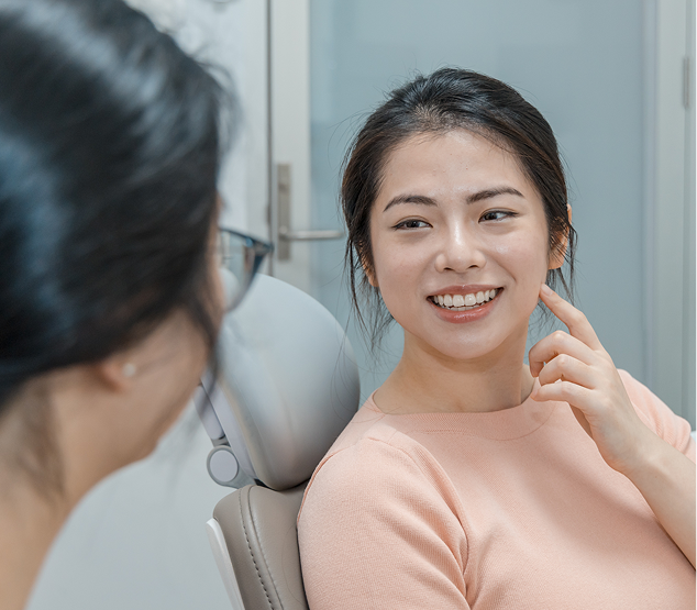 A dentist assessing a patient pointing to her jaw where she might feel gum disease discomfort.