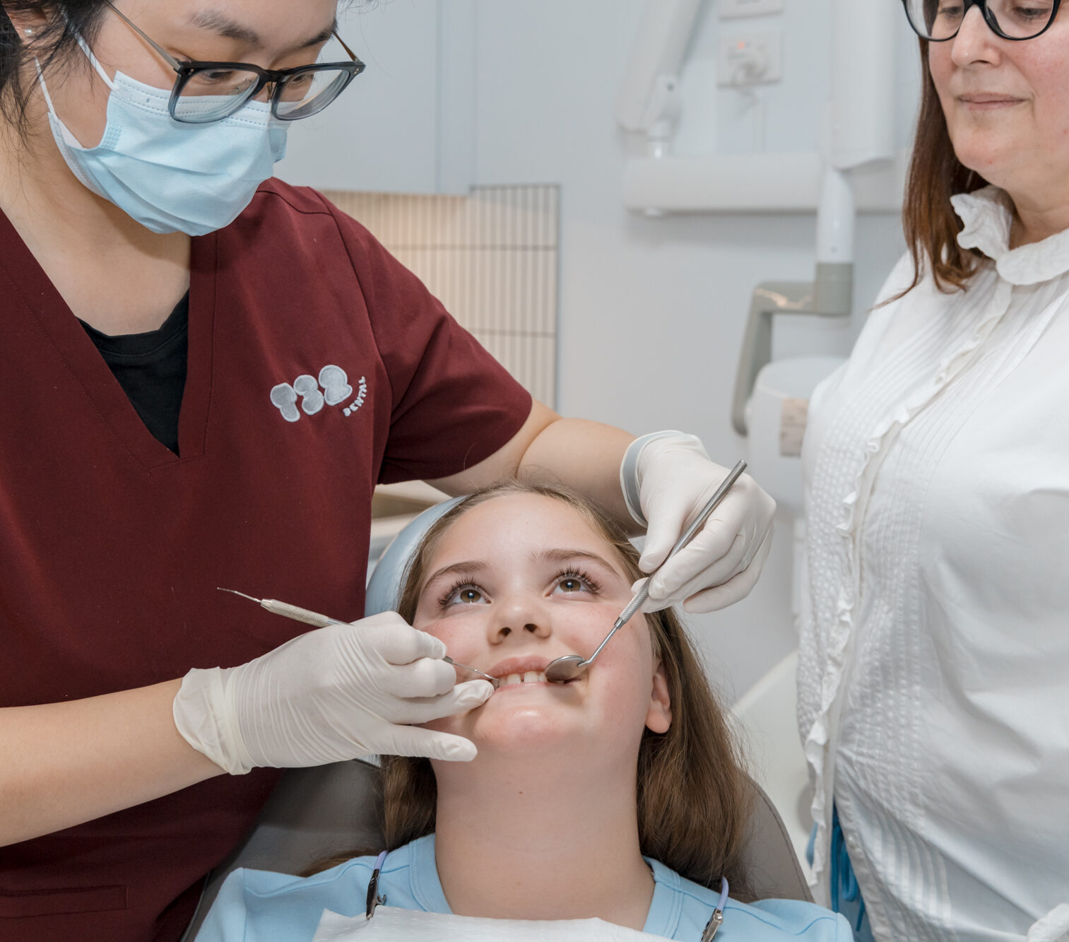 Dentist checking a young patient's teeth during a porcelain veneer assessment at a dental clinic.