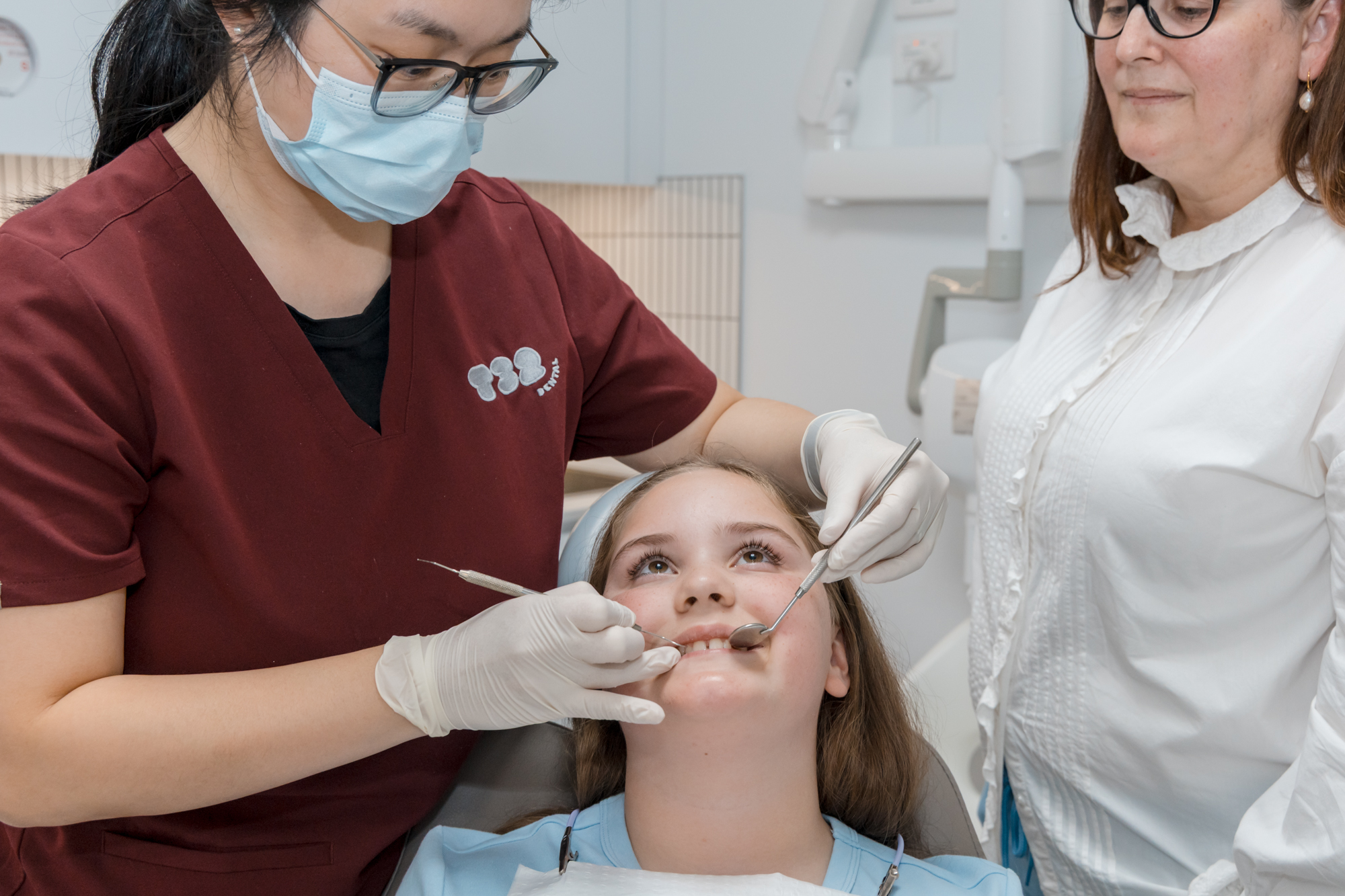 Dentist checking a young patient's teeth during a porcelain veneer assessment at a dental clinic.