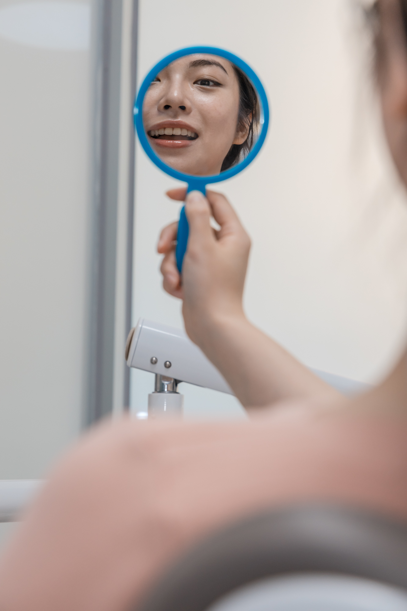 Dental patient inspecting her teeth in the mirror after being fitted for custom night guards.